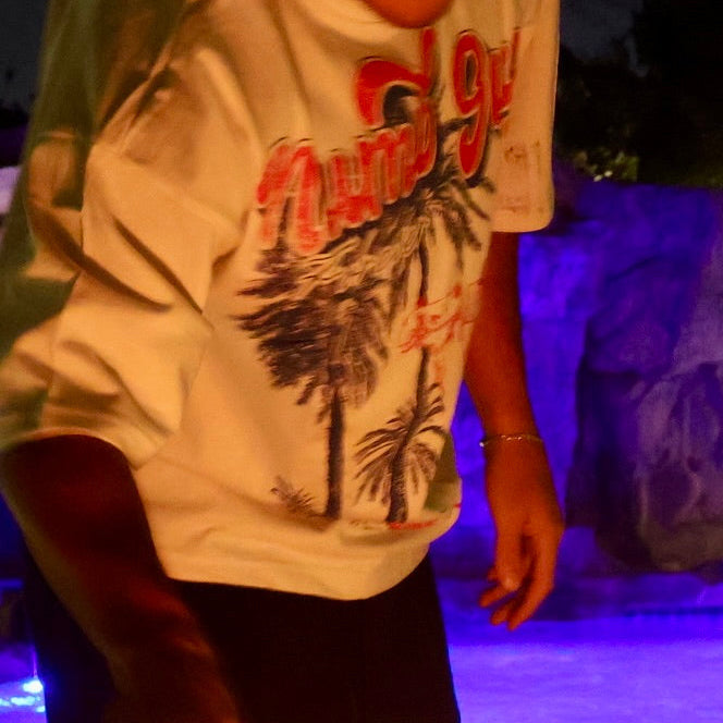 Person by a fire pit with a pool and illuminated wall in the background